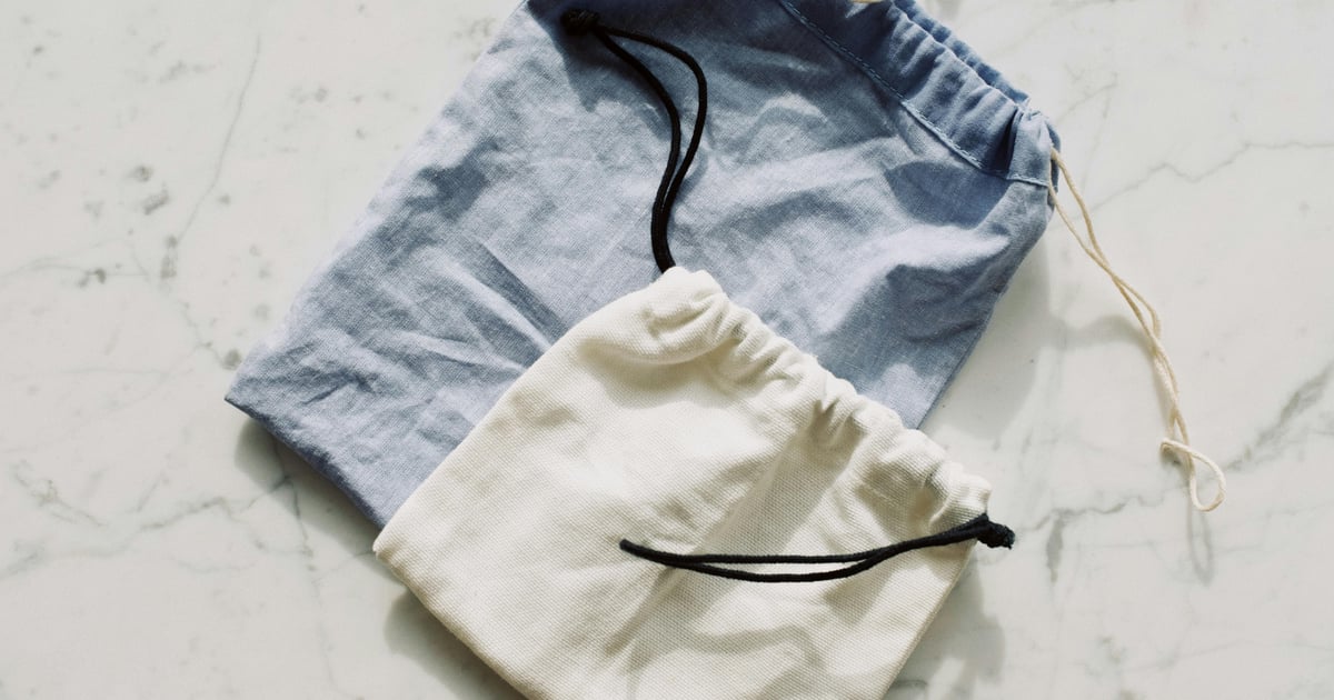 Two canvas drawstring bags in blue and white on a marble surface, ideal for eco-friendly storage.