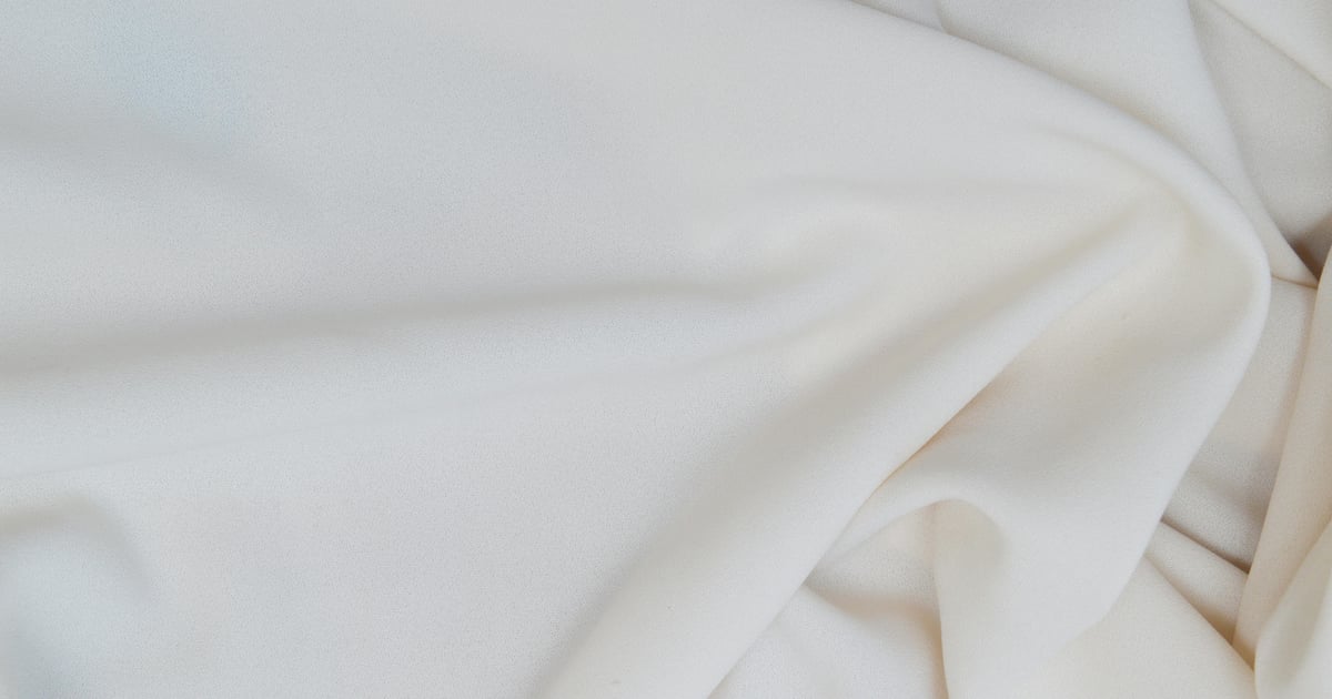 Close-up of soft white satin fabric showcasing elegant textures and gentle wrinkles.