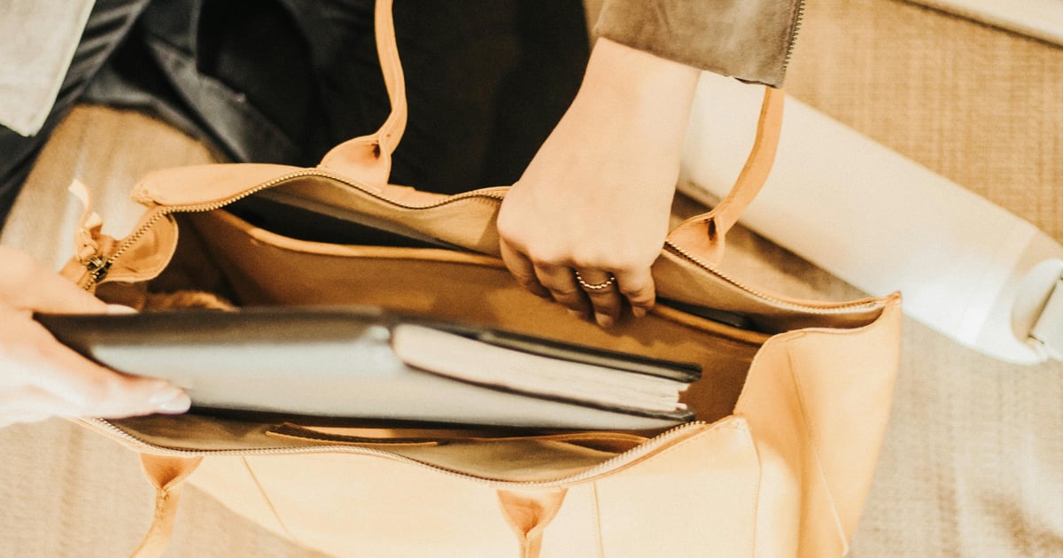 An elegant leather tote bag containing a laptop and notebook, perfect for travel or business use.