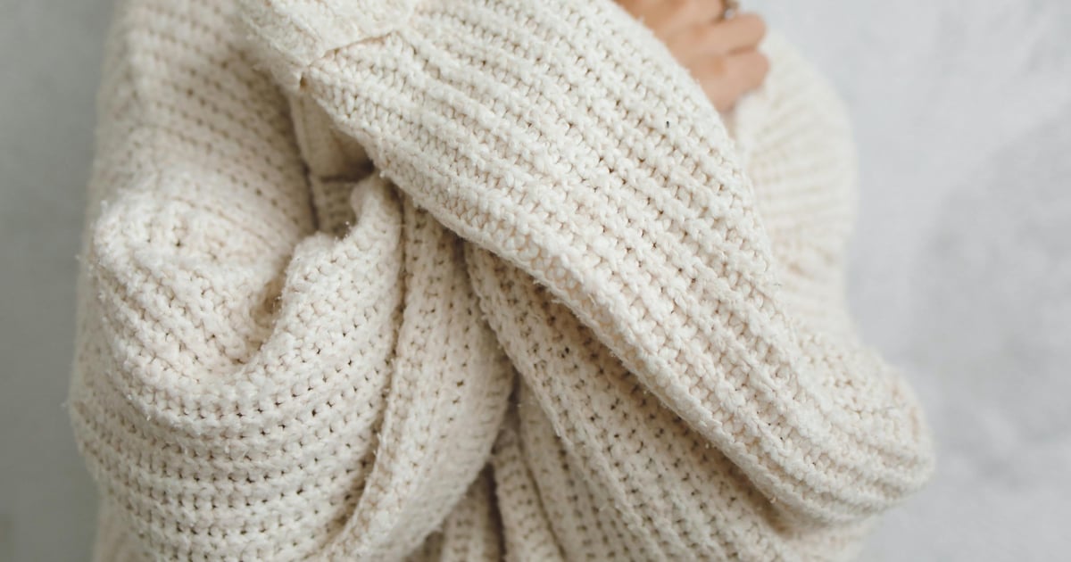 A close-up portrait of a person in a white knitted sweater with long sleeves, offering a warm and cozy feel.